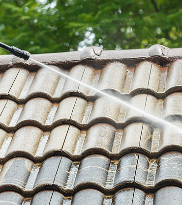 Water jet nozzle spraying roof tile during roof cleaning